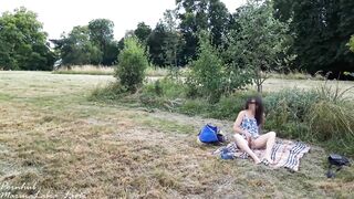 Insertion risqué d'un gros sex-toy en verre, dans un parc public avec des gens derrière l'herbe