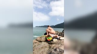 Redhead married to her liberal blond ally on a deserted beach rocks.