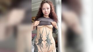 Tattooed woman lifts shirt to expose abdomen and haunches ?