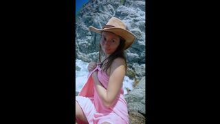 This gal smiles topless by the rocky shore ?