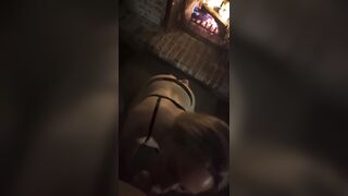 Golden-haired in ebony belt gives oral job by a fire