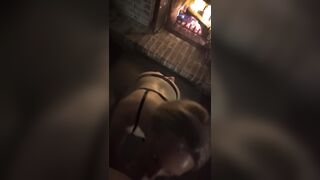 Golden-haired in ebony belt gives oral job by a fire