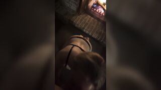 Golden-haired in ebony belt gives oral job by a fire