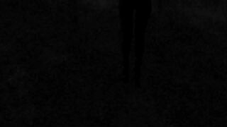 Walking on the wood wearing a ebony suit, hose and high heels ankle boots