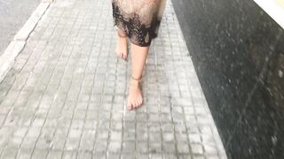 youthful female hippie is walking barefoot in public street