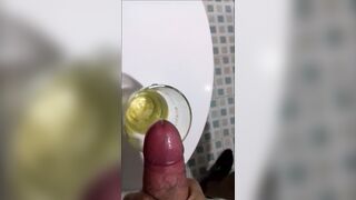 A chap in sweatpants voids urine and cums in a glass for his ally, who then drinks it